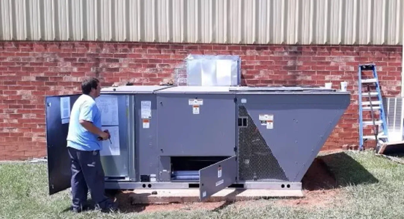 HVAC Blog 1 Technician inspecting a large commercial air conditioning unit outside a building.